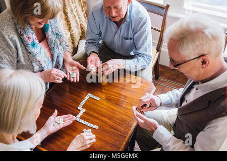 Sind eine Gruppe von älteren Freunden spielen Domino an einem Tisch zusammen. Stockfoto