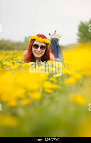 Das Mädchen liegt auf die unscharfen Bereich der Löwenzahn Stockfoto