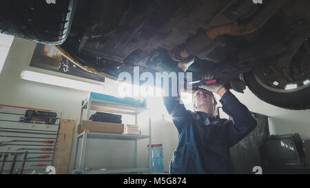 Mechanischer Auto Werkstatt - ein Mechaniker prüft die Aussetzung der Auto, Weitwinkel Stockfoto