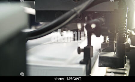 Gedruckte Blätter werden in der Druckmaschine serviert. Offset, CMYK, Nahaufnahme Stockfoto