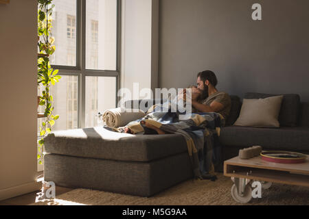 Paar küssen einander im Wohnzimmer Stockfoto