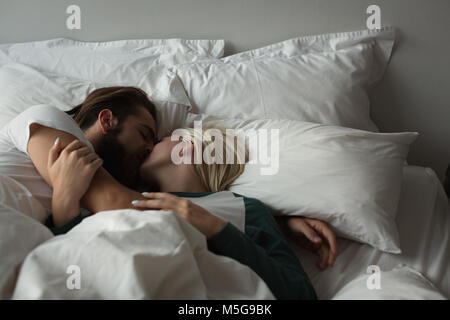 Paar küssen einander im Schlafzimmer Stockfoto