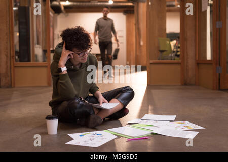 Weibliche Executive bei Dokumenten in Office suchen Stockfoto