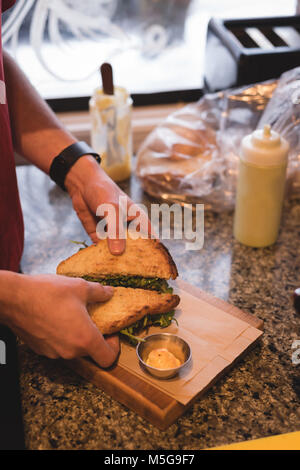 Männliche kellner Vorbereitung sandwich im Cafe Stockfoto