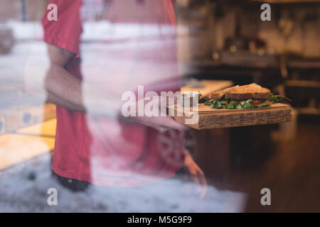 Männliche Kellner holding Sandwich im Cafe Stockfoto