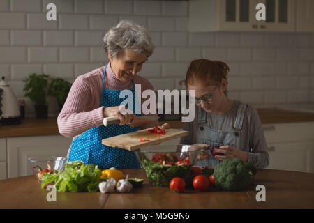 Großmutter und Enkelin Schneiden von Gemüse in der Küche Stockfoto