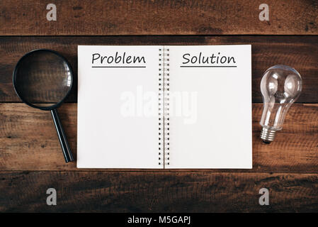 Lupe, Lampe und Notebook geschrieben PROBLEM UND LÖSUNG mit Kopie Speicherplatz auf Holztisch. problem Konzept Lösung Stockfoto