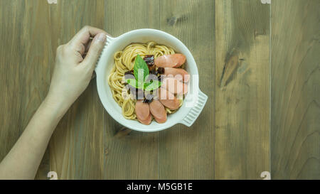 Spaghetti mit Wurst und getrocknete Paprika, würzig und scharf auf hölzernen Hintergrund, Ansicht von oben Stockfoto