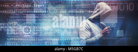 Das zusammengesetzte Bild des Hackers mit Laptop, während Sie Kreditkarte Stockfoto