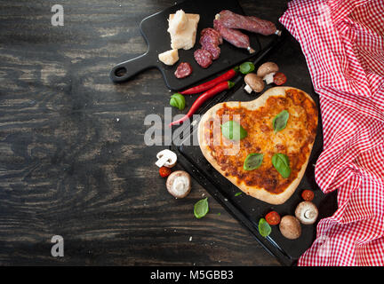 Pizza Margherita in Form eines Herzens auf rustikalen hölzernen Hintergrund Stockfoto