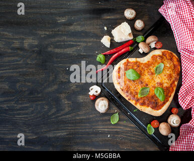 Pizza Margherita in Form eines Herzens auf rustikalen hölzernen Hintergrund Stockfoto