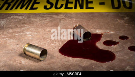 Zwei Pistole Muscheln und Blut auf einem beigen Fliesen mit Tatort Band hinter Stockfoto