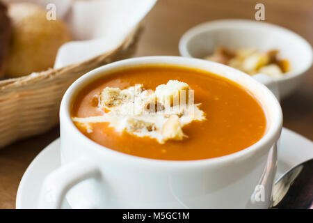 Tomatenmark Suppe mit Sahne und Cracker in einem weißen Teller auf dem Tisch Stockfoto