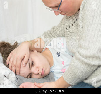 Ein Kind mit Epilepsie während eines Anfalls gepflegt, von einem qualifizierten Betreuer. Stockfoto