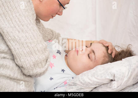 Ein Kind mit Epilepsie während eines Anfalls gepflegt, von einem qualifizierten Betreuer. Stockfoto