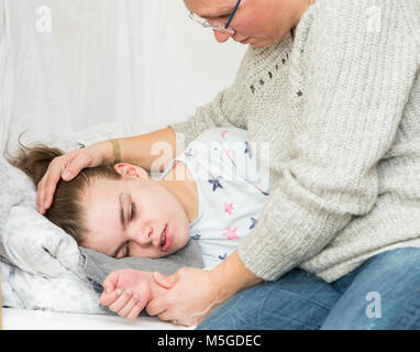 Ein Kind mit Epilepsie während eines Anfalls gepflegt, von einem qualifizierten Betreuer. Stockfoto