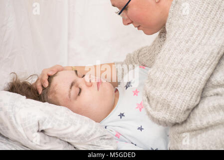 Ein Kind mit Epilepsie während eines Anfalls gepflegt, von einem qualifizierten Betreuer. Stockfoto