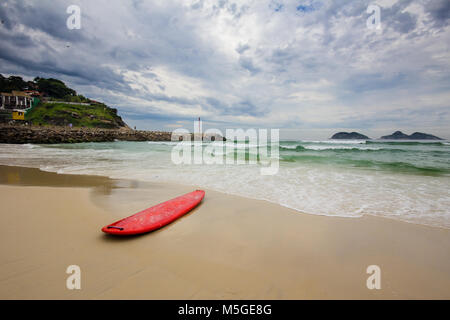 Red surfboard Verlegung auf shorebreak in Barra da Tijuca Strand Stockfoto