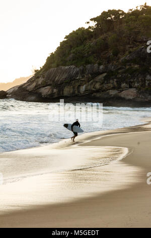 Silhouette der Surfer zu Fuß am Strand bei Sonnenuntergang Strand in Barra da Tijuca, Rio de Janeiro Stockfoto