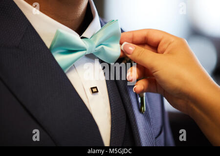 Einstellung der Frau die Hände des Bräutigams bowtie in Nahaufnahme Stockfoto