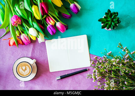 Frohe Ostern Frühling Schuß von oben als flatlay mit leeren Notebook für Meldung und bunte Tulpen, Blumen und Kaffee Tasse Stockfoto