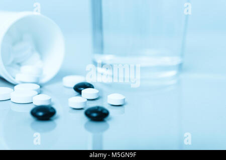 Pharmazeutische Behandlung Hintergrund - Gruppen von Pillen und Glas Wasser in Nahaufnahme (blaue Filter Effekt) Stockfoto