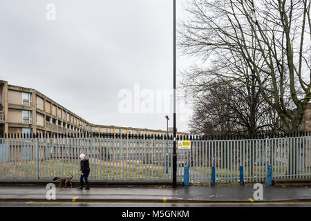 Frau und ihr Hund vorbei gehen Sicherheit Zäune rund um das Gehäuse, das unsichere erklärt wurde. Park Hill Wohnungen, Sheffield, England, Großbritannien Stockfoto