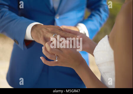 Die Braut trägt ein Hochzeit Ring auf den Bräutigam. Nahaufnahme Stockfoto