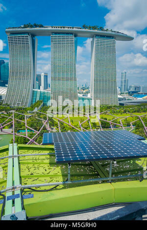 Singapur, Singapur - Januar 30, 2018: in der Nähe von Solar Paneel mit einer schönen Landschaft der drei Türme des Marina Bay Sands Ressort gegen einen bewölkten Himmel hinter, die Welten der teuerste standalone Casino zum Zeitpunkt der Eröffnung im Jahr 2010 in Singapur Stockfoto