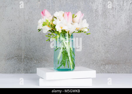 Fressia und Tulpe Blumen in einem blauen Glas Stockfoto