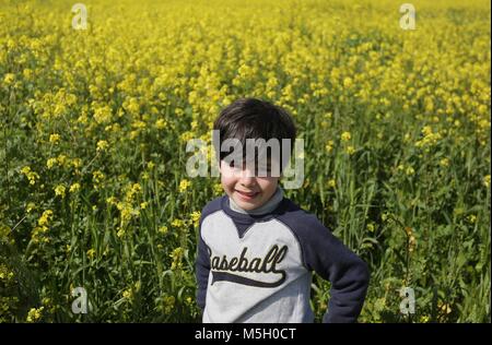 Gaza, Gazastreifen, palästinensischen Gebiet. 23 Feb, 2018. Ein palästinensisches Kind spielt zwischen Blumen, die in Feldern in Gaza Stadt wachsen am 23 Februar, 2018 Credit: Ashraf Amra/APA-Images/ZUMA Draht/Alamy leben Nachrichten Stockfoto