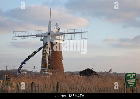 Norfolk Broads, UK. 23. Februar 2018. Horsey Windpump Entwässerung Mühle erhält es Vertrieb zurück nach vier Jahren entfernt wird, Teil einer National Trust Restaurierungsprojekt. Aufgrund der weichen Boden ein Tieflader mit Hiab Kran wurde verwendet, um die Verkäufe nacheinander in die richtige Position zu heben. Millwright Tim Wittling und seine Crew arbeitete für fast 12 Stunden in dem sehr kalten und eine leichte Brise, die Sicherung der letzten Segel in der Abenddämmerung. Die Fensterläden sind neben neu installiert werden und es wird gedacht, dass der Umsatz wieder drehen bis Juni. Foto: Adrian Buck/Alamy Leben Nachrichten. Stockfoto