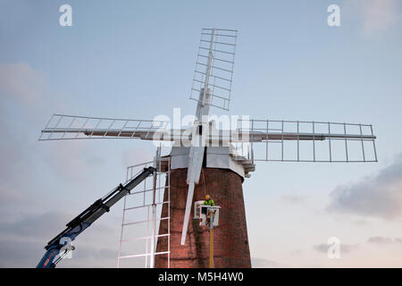 Norfolk Broads, UK. 23. Februar 2018. Horsey Windpump Entwässerung Mühle erhält es Vertrieb zurück nach vier Jahren entfernt wird, Teil einer National Trust Restaurierungsprojekt. Aufgrund der weichen Boden ein Tieflader mit Hiab Kran wurde verwendet, um die Verkäufe nacheinander in die richtige Position zu heben. Millwright Tim Wittling und seine Crew arbeitete für fast 12 Stunden in dem sehr kalten und eine leichte Brise, die Sicherung der letzten Segel in der Abenddämmerung. Die Fensterläden sind neben neu installiert werden und es wird gedacht, dass der Umsatz wieder drehen bis Juni. Foto: Adrian Buck/Alamy Leben Nachrichten. Stockfoto