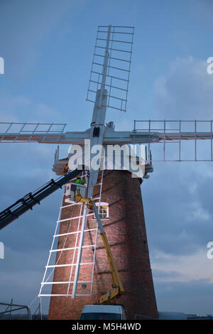 Norfolk Broads, UK. 23. Februar 2018. Horsey Windpump Entwässerung Mühle erhält es Vertrieb zurück nach vier Jahren entfernt wird, Teil einer National Trust Restaurierungsprojekt. Aufgrund der weichen Boden ein Tieflader mit Hiab Kran wurde verwendet, um die Verkäufe nacheinander in die richtige Position zu heben. Millwright Tim Wittling und seine Crew arbeitete für fast 12 Stunden in dem sehr kalten und eine leichte Brise, die Sicherung der letzten Segel in der Abenddämmerung. Die Fensterläden sind neben neu installiert werden und es wird gedacht, dass der Umsatz wieder drehen bis Juni. Foto: Adrian Buck/Alamy Leben Nachrichten. Stockfoto