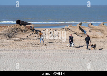 Hundebesitzer ihre Hunde zu Fuß am Strand im Sand auffüllen/Strand Nahrung Projekt breitere Strände an der Belgischen Küste zu machen Stockfoto