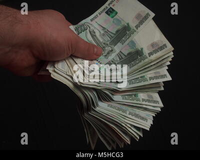 Banknoten im Wert von 1000 Rubel in der Hand einer Person. Das Geld ist in der Form eines Fächers gestapelt. Close Up. Stockfoto