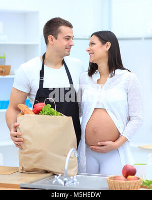 Mann und seine schwangere Frau sind Kämmen durch die Pack, stehen in der Küche Stockfoto