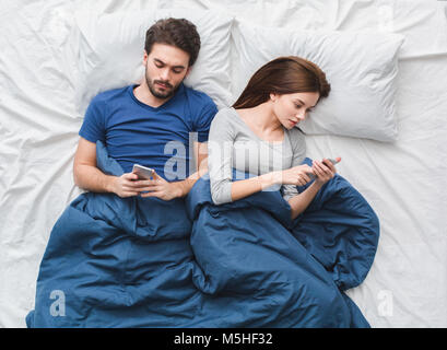 Junges Paar im Bett Top View morgen Konzept Telefon süchtig Stockfoto