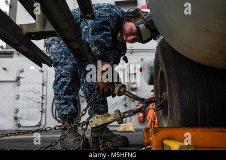 MANAMA, Bahrain (Jan. 30, 2018) der Luftfahrt Bootsmann Mate (Handling) Airman Garret Wilbanks Bindungen nach einem MH-60R Seahawk auf dem Flugdeck an Bord der Flugzeugträger USS Theodore Roosevelt (CVN 71). Theodore Roosevelt und ihre Carrier strike Group werden in den USA 5 Flotte Bereich für Maßnahmen zur Erhöhung der Sicherheit im Seeverkehr im Einsatz Verbündeten und Partnern zu beruhigen und der Freiheit der Schiffahrt und des freien Handels in der Region erhalten. (U.S. Marine Stockfoto