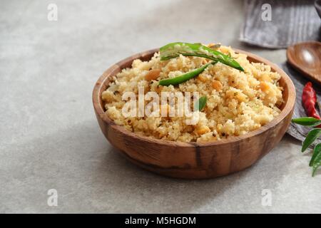 Rava Upma - südindischer Frühstück mit Grieß in eine hölzerne Schüssel serviert. Stockfoto