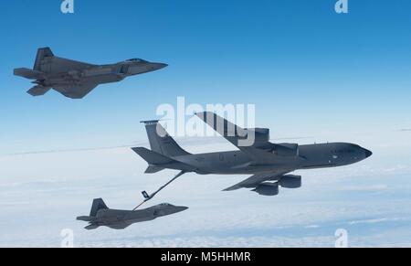 Einer KC-135 Stratotanker von der 101St Air Refuelling Flügel tankt F-22 Raptors aus der 94th Fighter Squadron über den Atlantik, 22. Februar 2018. Die stratotanker ermöglicht Kampfflugzeuge wie die F-22 Raptor global Power durch die Dominanz, die verstärkte Unterstützung aus der Luft und Luftüberlegenheit zur Verfügung zu stellen. (U.S. Air Force Foto von Tech. Sgt. Natasha Stannard) Stockfoto