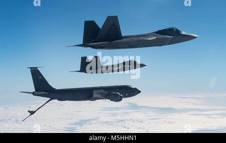 Einer KC-135 Stratotanker von der 101St Air Refuelling Flügel fliegen in Formation mit F-22 Raptors aus der 94th Fighter Squadron über den Atlantik, 22. Februar 2018. Diese Luftbetankung wurde als Training Mission sowohl der Tanker Crew und die Raptor-Piloten, die gute Kenntnisse in den technischen Spielraum gewonnen durchgeführt. (U.S. Air Force Foto von Tech. Sgt. Natasha Stannard) Stockfoto