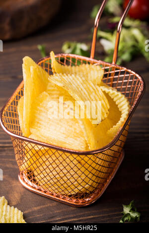 Knusprige Kartoffelchips in Kupfer Warenkorb auf alten hölzernen Hintergrund serviert mit Club Sandwich. Gesundes fast food Konzept. Stockfoto