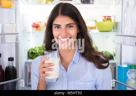 Porträt eines lächelnden jungen Frau mit Glas Milch Stockfoto