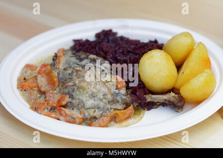 Gebratene Entenkeule mit gedünstetem Rotkohl, gekochte Kartoffel, Karotte unter weißen Sauce in einem Street Food Restaurant Stockfoto