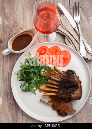 Gebratenes Lamm Rippen mit Rucola und Tomaten auf einer rustikalen Tisch Stockfoto