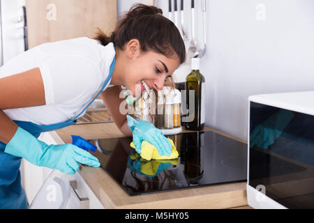 Gerne weibliche Hausmeister Reinigung Induktion Herd in der Küche Stockfoto