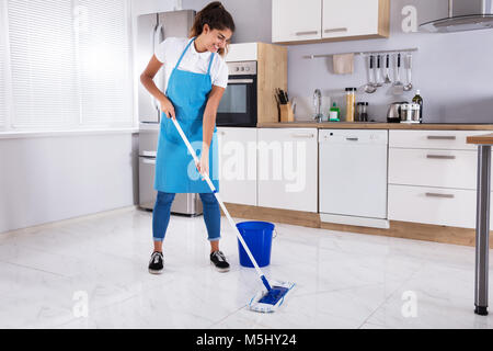 Glückliche Frau Reinigung Boden mit Mop in der Küche zu Hause. Stockfoto