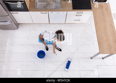 Glückliche Frau Reinigung Boden mit Mop in der Küche zu Hause. Stockfoto