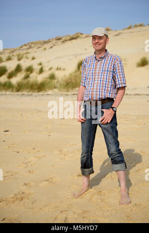 Reifer Mann in Freizeitkleidung ruht auf einem Sandstrand gegen die Düne von Pilat, Frankreich Stockfoto